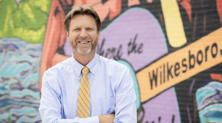 Board chair Ken Noland posing in front of a mural in Wikesboro, NC.