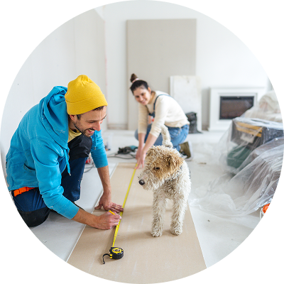 Young couple and their dog working together on a home remodel, measuring and cutting drywall with tools, preparing to install plasterboard—consider using a Civic HELOC for your next home project.