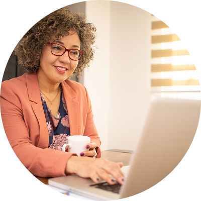 Older woman working at a desk, looking at her laptop while reviewing her retirement accounts.