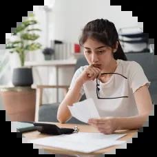 A woman reviewing bills at her table, focused and determined as she makes plans to get out of judgment debt.