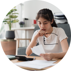 A woman reviewing bills at her table, focused and determined as she makes plans to get out of judgment debt.