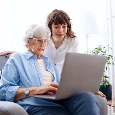 Older woman on laptop getting help from daughter to block and report a phishing email. 