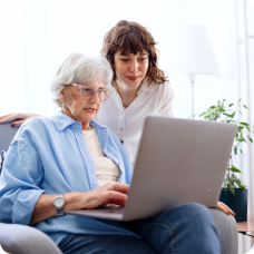 Older woman on laptop getting help from daughter to block and report a phishing email. 