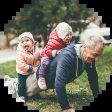 A grandfather doing a push-up with two small children laughing on his back, symbolizing strength and legacy; conceptually tied to the idea of protecting family wealth through an irrevocable trust.