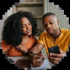  couple sitting at a kitchen table reviewing finances with a calculator and notepad, planning a rainy day fund on a gloomy day.