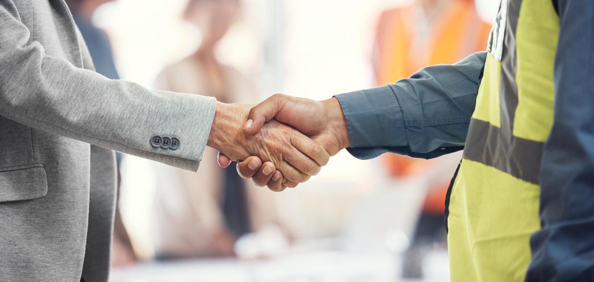 A diverse team of professionals celebrates a workplace achievement with a high-five in a modern office. 