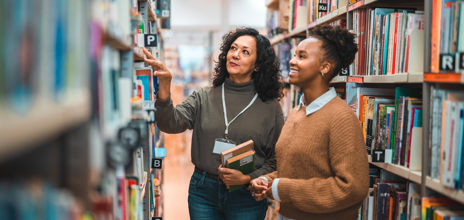 Librarian training a volunteer on how to organize the library books on the shelfs. 