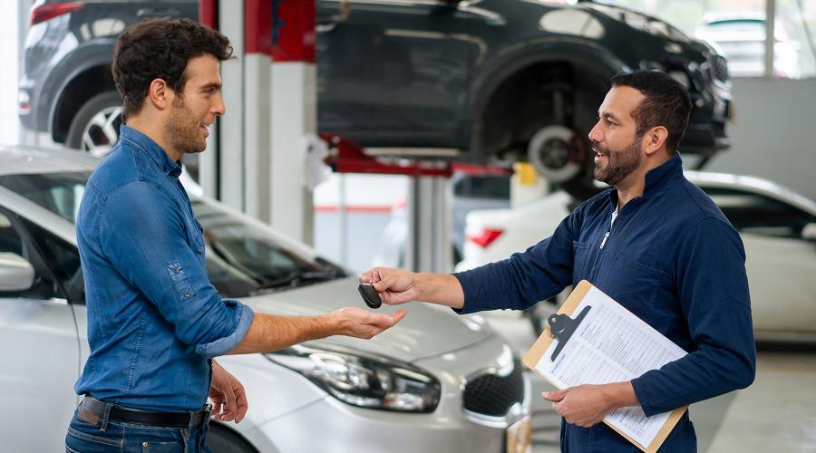 Man picking up his car at the auto repair shop and getting the keys from the mechanic