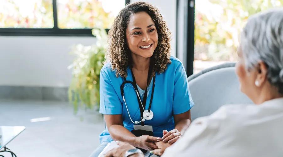 Healthcare worker sitting with a patient.