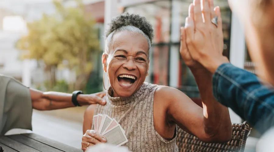 A woman plays cards and high-fives a friend, feeling confident knowing her Civic personal loan is protected with the added security of credit insurance.
