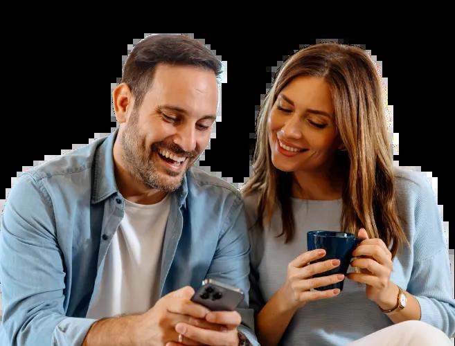 Happy couple enjoying morning coffee and smiling after seeing their paychecks deposited 3 days early.