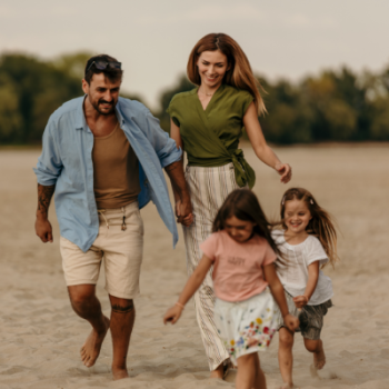 Happy parents are having fun with their two little girls on the beach.