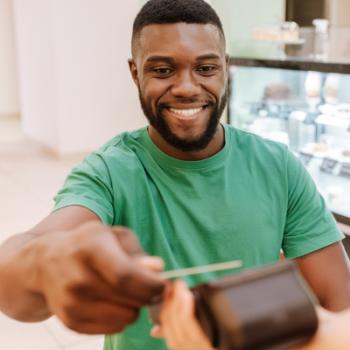 Man tapping his Civic Checking Visa debit card to pay for coffee. 