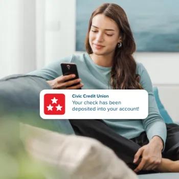 Woman receiving a push notification alerting of direct deposit into account.