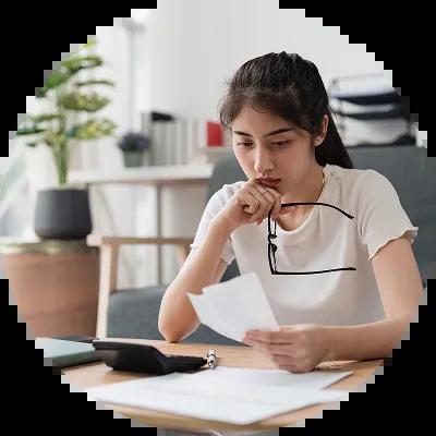 A woman reviewing bills at her table, focused and determined as she makes plans to get out of judgment debt.