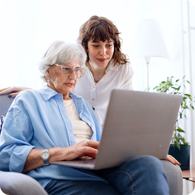 Older woman on laptop getting help from daughter to block and report a phishing email. 