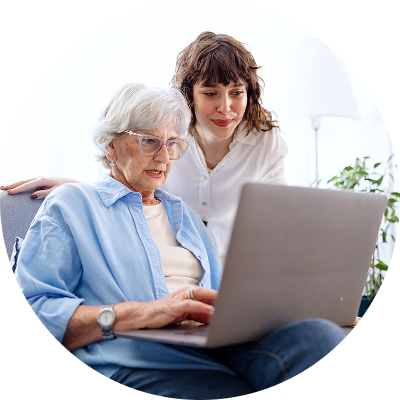 Older woman on laptop getting help from daughter to block and report a phishing email. 