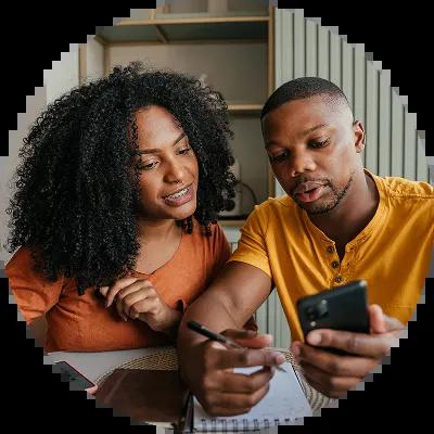  couple sitting at a kitchen table reviewing finances with a calculator and notepad, planning a rainy day fund on a gloomy day.