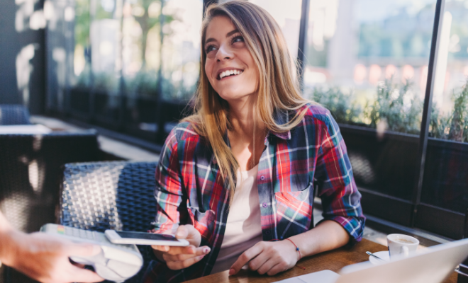 Woman in cafe making contactless payment with Civic Bonus Checking debit card.