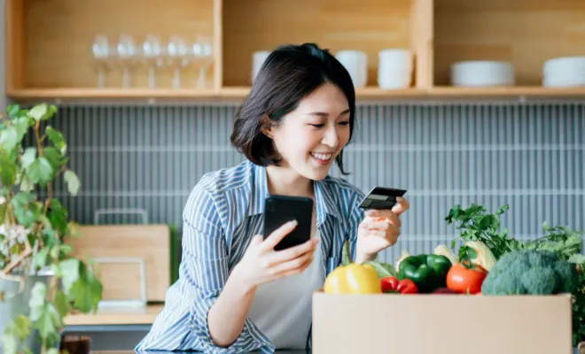 Smiling young Asian woman shopping online with her Civic Business Rewards Credit Card.