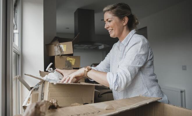 Smiling woman unpacking boxes in her new home, enjoying the stability and predictability of a fixed-rate mortgage with Civic Credit Union.
