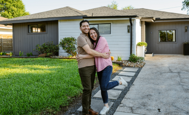 Couple posing in front of their newly purchased home.