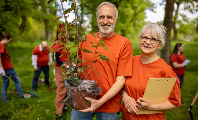 Senior couple preparing to plant a tree in their local park.