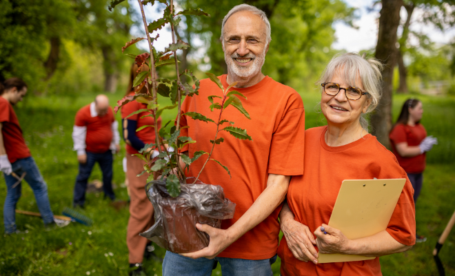 Senior couple preparing to plant a tree in their local park.