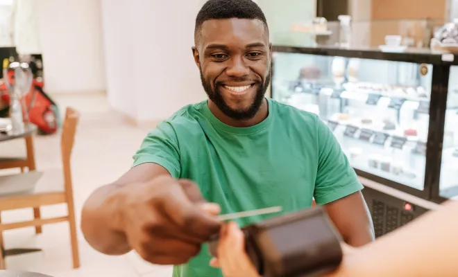 Man tapping his Civic Bonus Checking Visa debit card to pay for coffee. 