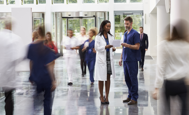 Healthcare workers and volunteers discussing the benefits of Civic membership in a busy hospital setting.