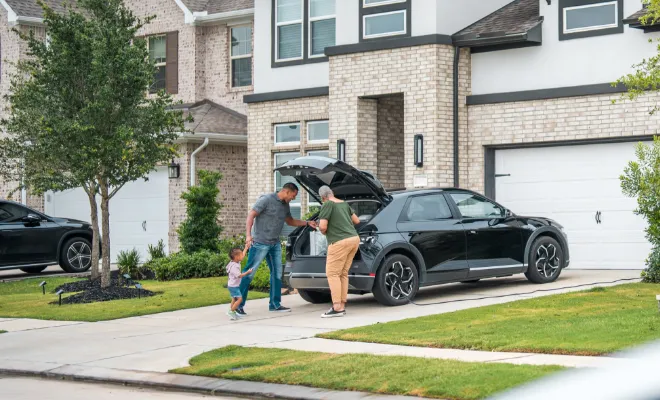 A family carrying bags from their car into the house—everyday moments protected with home and auto insurance through TruStage.