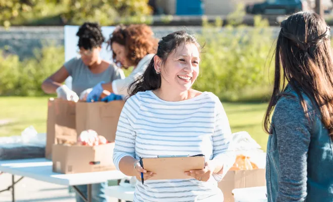 A woman holding a clipboard, recruiting volunteers for her nonprofit, knowing that a her Civic Nonprofit Money Market Account helps grow savings faster than a traditional savings account.