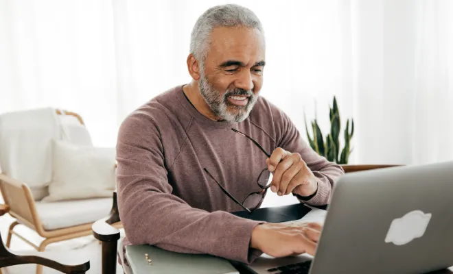 A gentleman using his laptop to sign up for a Civic Traditional IRA savings account.