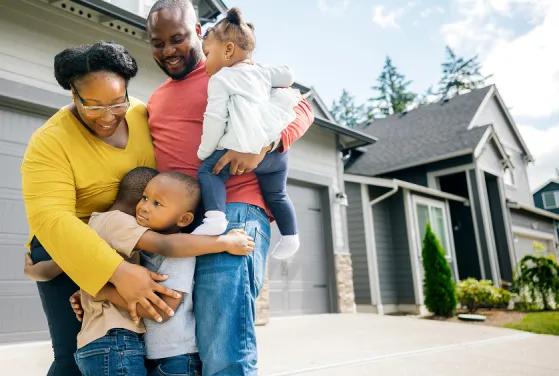 A family hugging in front of there new home. 