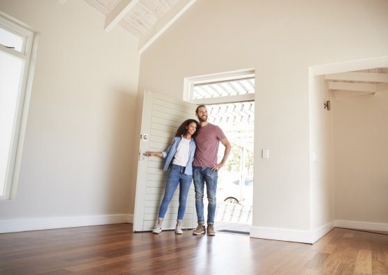 A woman and man enter an empty house they are thinking about buying and picture themselves living there.