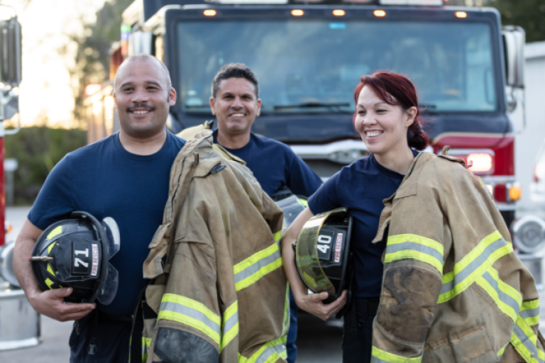 Three firefighters posing with their gear.