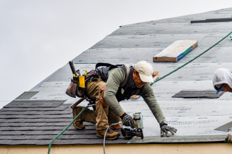 Man fixing a roof after natural disaster.