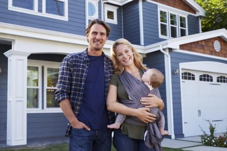 Smiling family in front of their new home, feeling good about locking in a fixed-rate mortgage with Civic Credit Union.