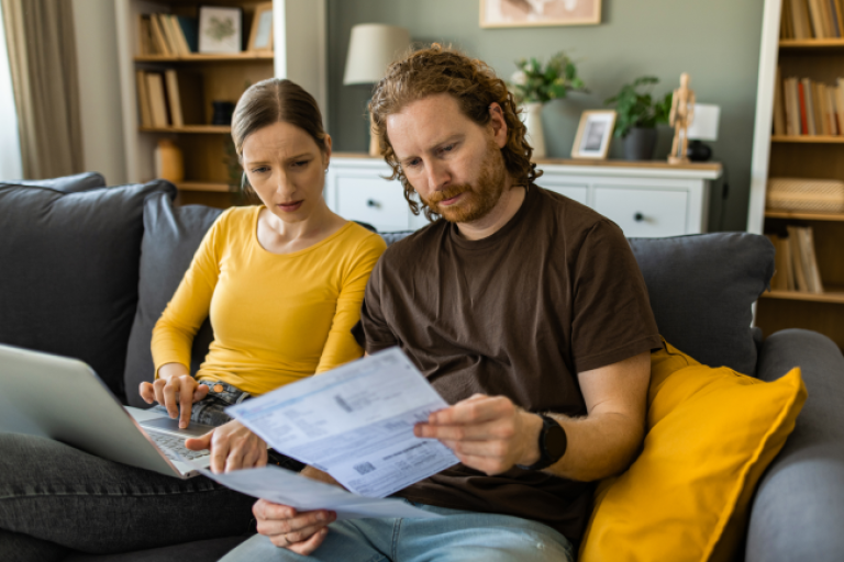 Stressed young adult couple managing home finances with laptop