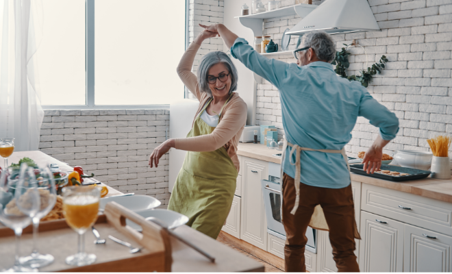 An older couple dancing in the kitchen, enjoying the moment while planning for their future with a Civic Roth IRA.