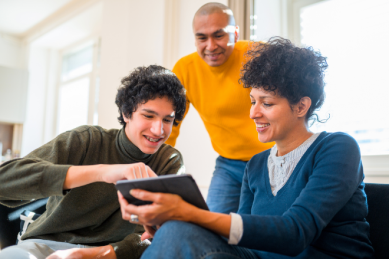 Parents showing their teen how to access his NexGen Checking account on his tablet.